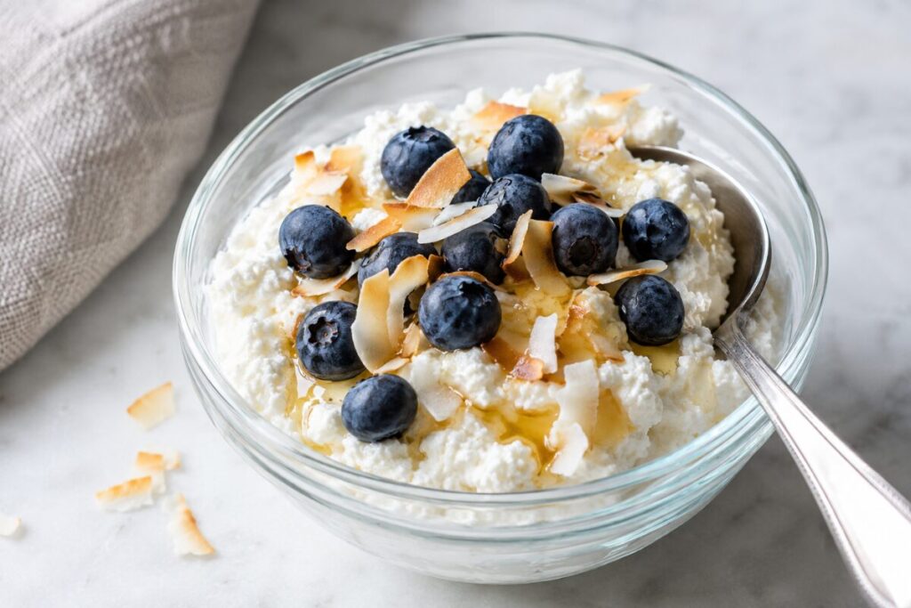 Ricotta bowl topped with blueberries, toasted coconut flakes, and honey drizzle.